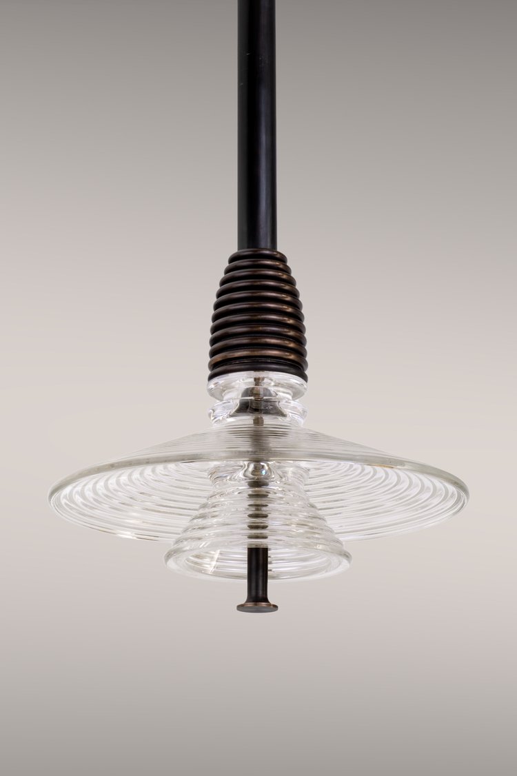 Insulator pendant light in dark brass and clear glass.