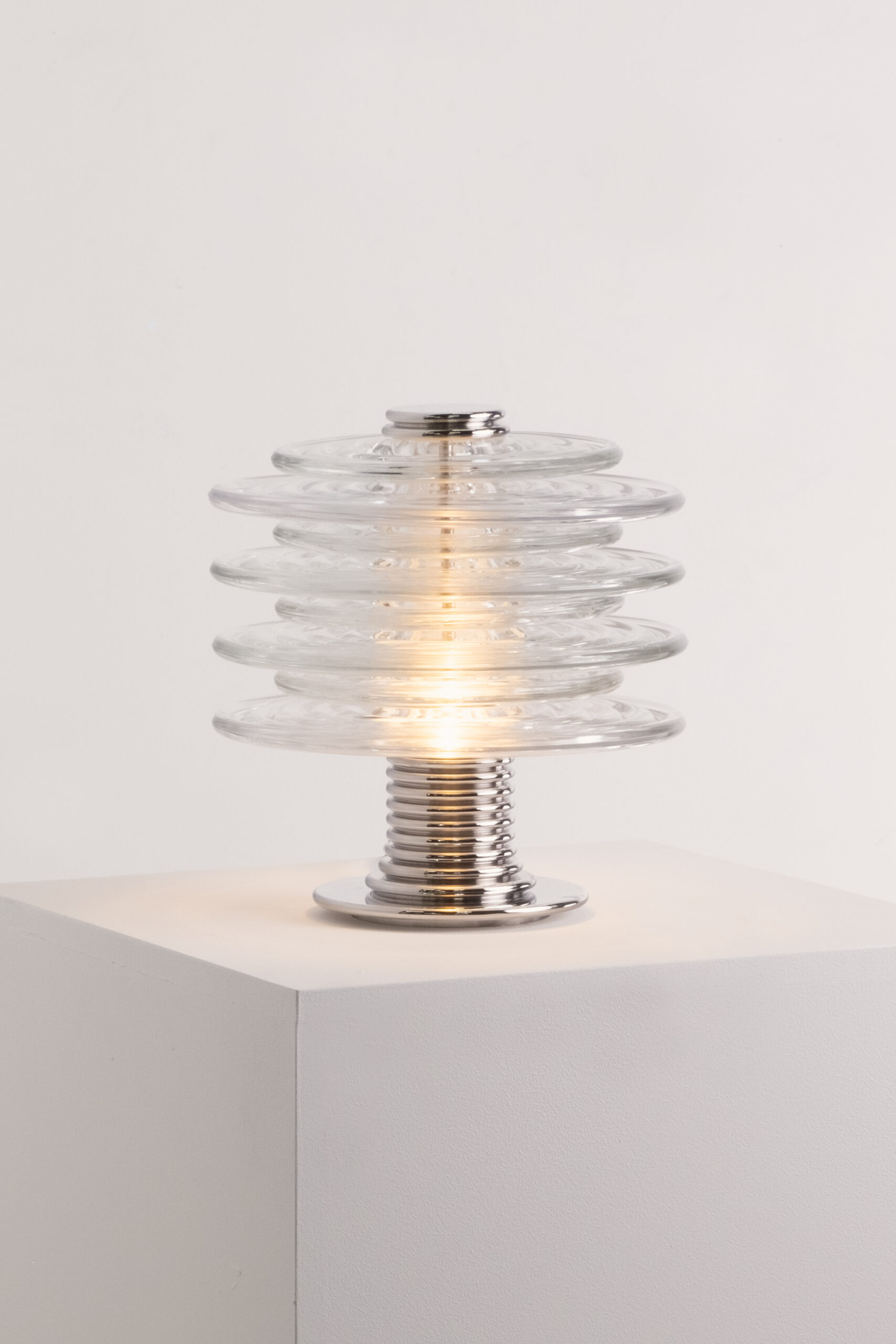 A ribbed, art-deco inspired table lamp in clear pressed glass and polished stainless steel.